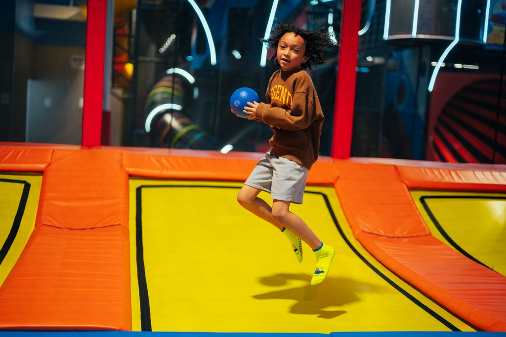 A kid is playing dodgeball on the trampoline at Lululand