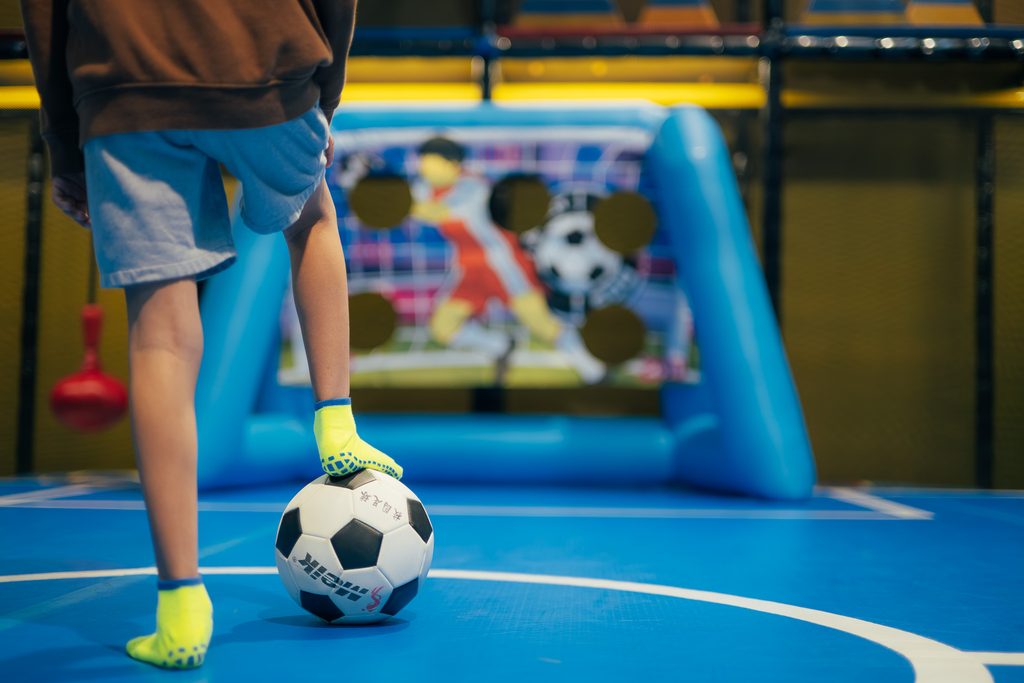 A kid is about to kick a soccer ball into Lululand's soccer court