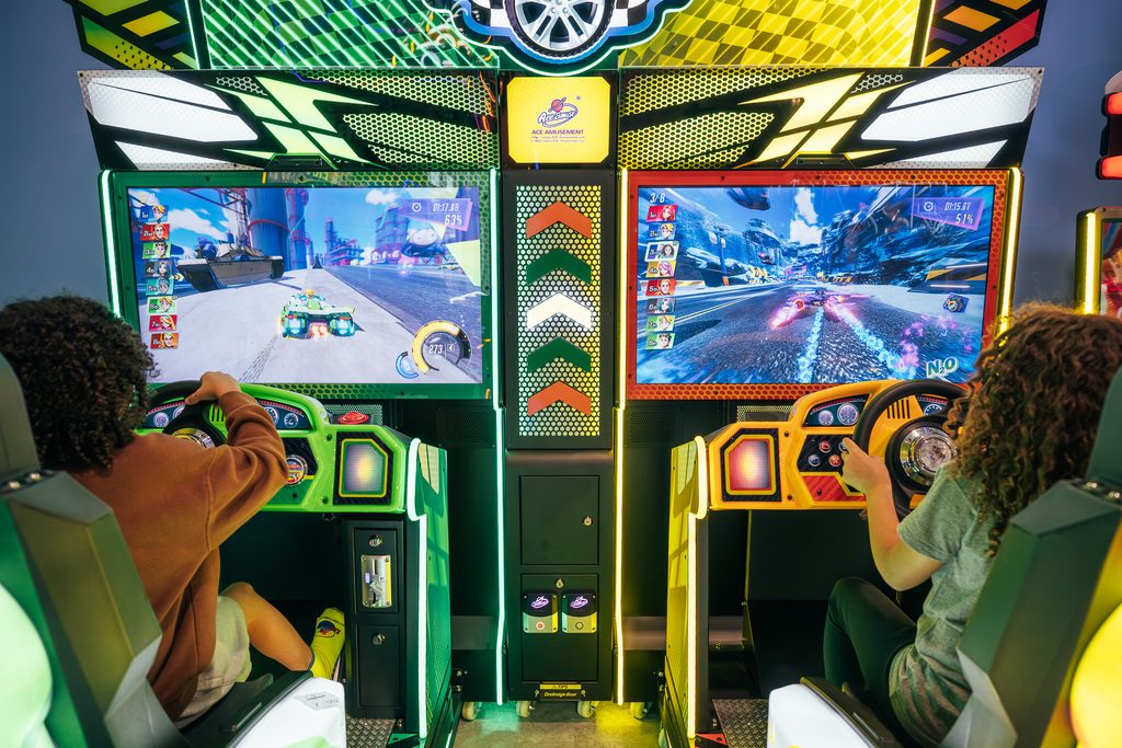 Two kids playing the race car simulator in arcade area