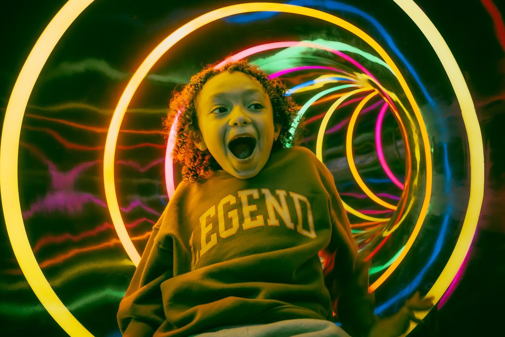 A kid is sliding down the the rainbow slide with lights