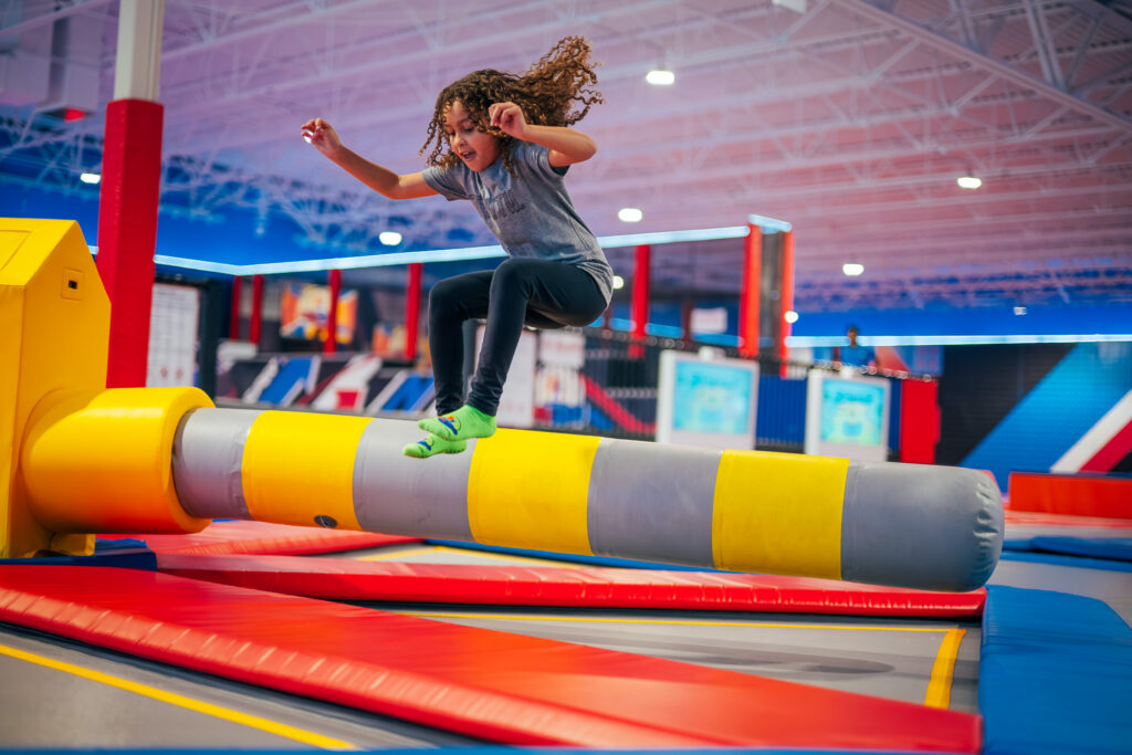 A girl playing the wipeout challenge with spinning bars and swinging pads